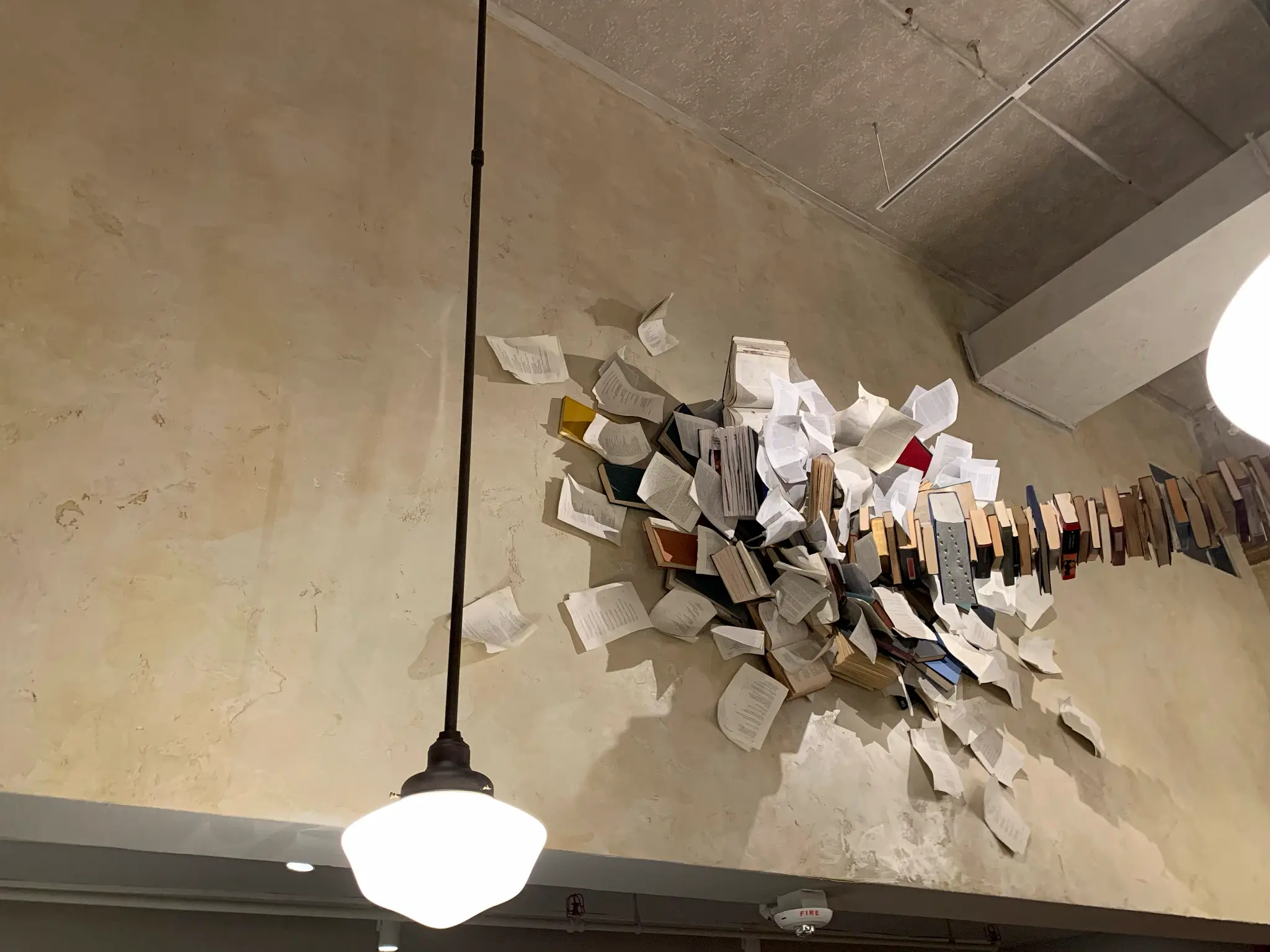 The Drama Book Shop — sculptural installation of books and torn pages on an aged plaster wall