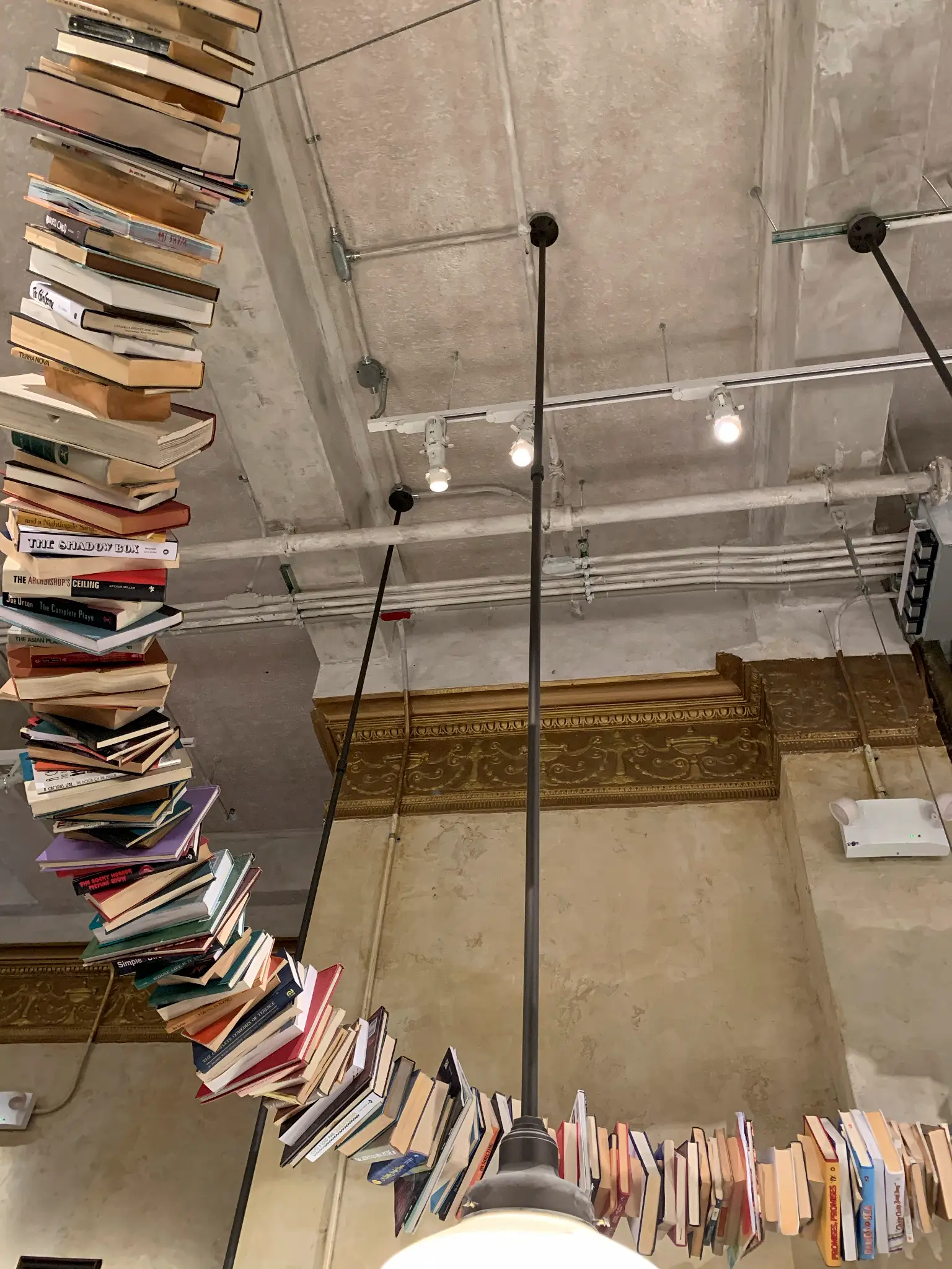 The Drama Book Shop — detail of the cascading book installation beside the original pressed-tin cornice