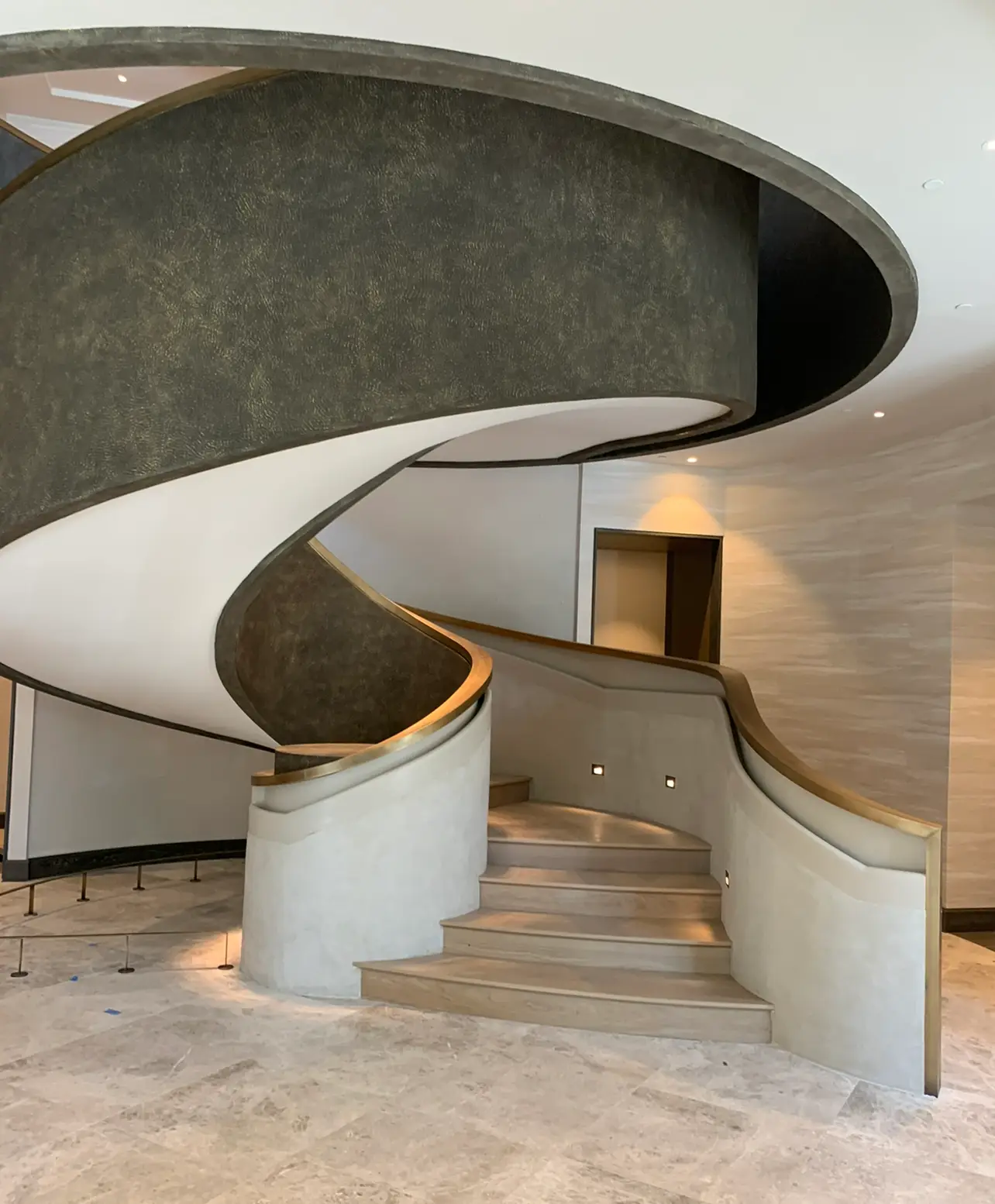 St. Regis Residences Rye — underside of the sculptural spiral stair in dark plaster