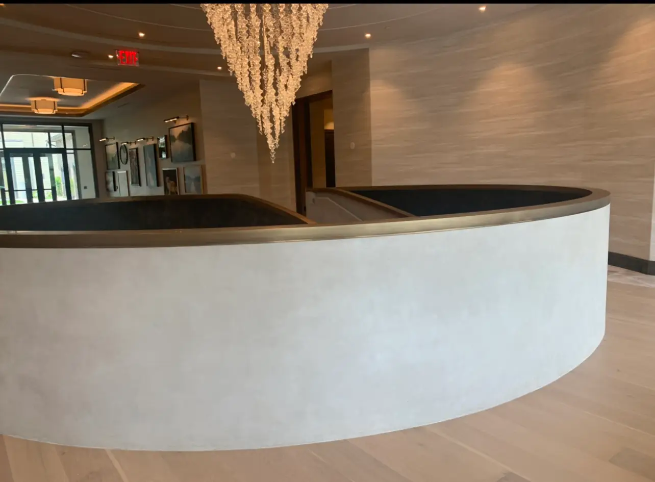 St. Regis Residences Rye — curved plaster stair enclosure beneath a crystal chandelier
